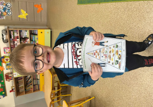 Chłpiec trzyma plansze edukacyjną