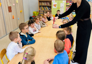 Dzieci siedzą przy stoliku i patrzą na eksperymenty