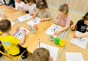 Dzieci wykonują pracę plastyczną- używając farb, słomek i pędzelków