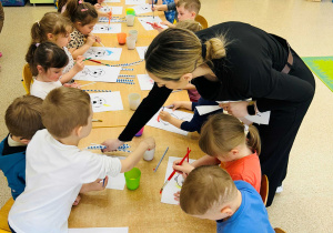 Dzieci wykonują pracę plastyczną- używając farb, słomek i pędzelków