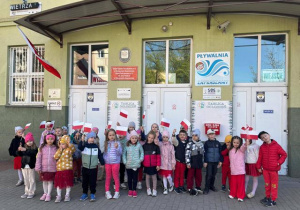 Przedszkolaki z flagami przed budynkiem SP 12