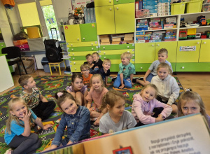 Dzieci słuchają jak czyta nauczyciel