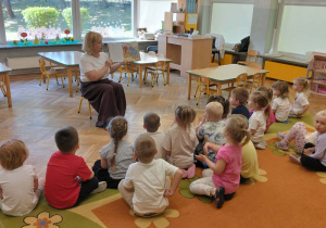 Dzieci słuchają bajki, którą czyta nauczycielka