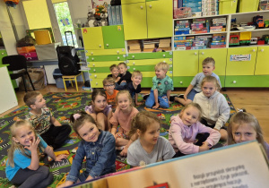 Dzieci słuchają jak czyta nauczyciel