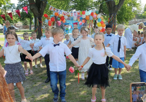 Dzieci trzymają się za ręce i tańczą poloneza