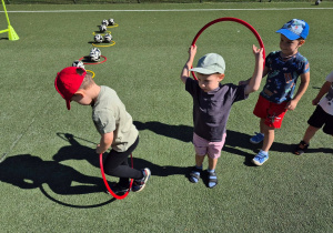 Dzieci podczas zajęć sportowych przechodzą przez hula hop