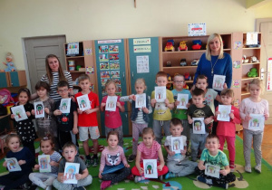 Zdjęcie przedszkolaków ze swoimi rysunkami i paniami