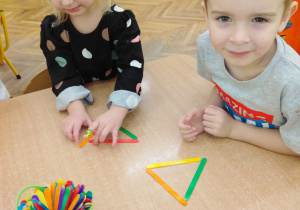 Chłopiec i dziewczynka układają trójkąty z patyczków