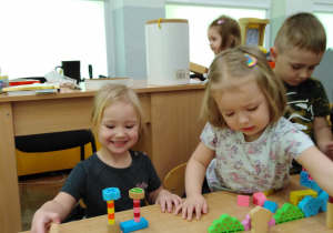 Dziewczynki tworzą budowle z drewnianych klocków