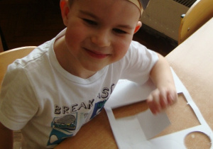 Chłopiec robi pracę plastyczną z figur geometrycznych
