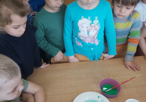 Dzieci obserwują malowanie kuli ziemskiej na mleku