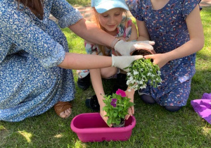Nauczycielka sadzi kwiaty z dziewczynkami