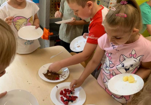 Dzieci przygotowują owoce z rozpuszczoną czekoladą