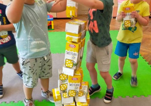 Przedszkolaki układają wieżę z kartonów po mleku