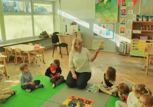 Dzieci słuchają opowiadania czytanego przez nauczycielkę