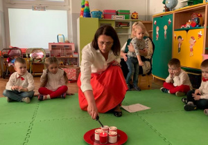 Nauczycielka zapala świeczki urodzinowe dla Polski