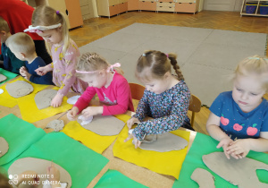 Przedszkolaki wycinają kształty z gliny