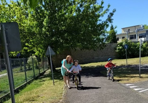 Dziewczynka z pomocą nauczycielki jedzie na rowerze