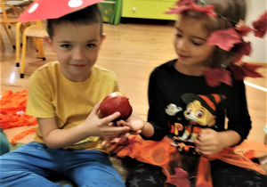 Dzieci podają sobie jabłko